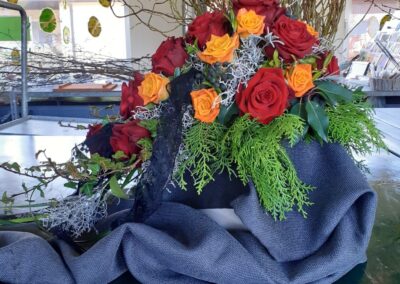 Tischdekoration, bestehend aus 2 Rosen-Sorten und einigen Pflanzen.