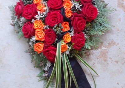 Herzförmiges Rosengesteck mit roten und orangen Rosen