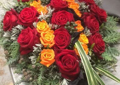 Herzförmiges Rosengesteck mit roten und orangen Rosen