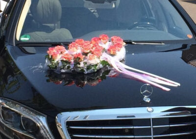 Pinker Rosenkranz auf einem schwarzen Mercedes