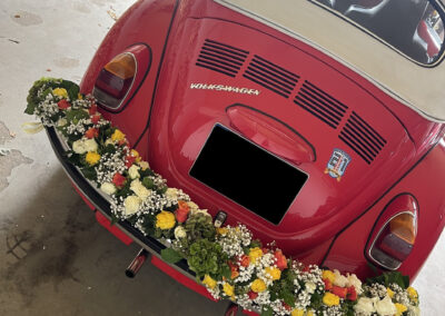 Girlanden an einem roten VW-Käfer.