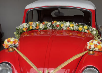 Girlanden an einem roten VW-Käfer.