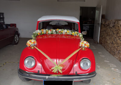 Girlanden an einem roten VW-Käfer.