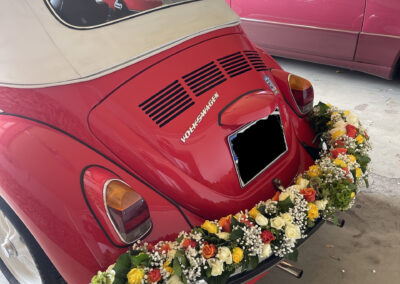 Girlanden an einem roten VW-Käfer.